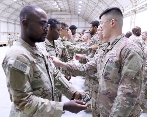 KUWAIT-- New York Army National Guard Soldiers assigned to the 642nd Aviation Support Battalion place the patch of the 185th Expeditionary Combat Aviation Brigade on the left shoulder of another Soldier's uniform during a unit patch ceremony on July 14 20