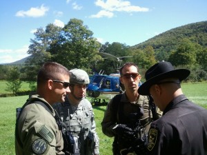 Lt. Col. Albert Thiem (center), of Ballston Spa, N.Y., Greene County Deputy Sheriff J.R. DelVecchio (right), and two New York State Police helicopter pilots coordinate the rescue of civilians trapped by Hurricane Irene floodwaters. Thiem belongs the New York Army National Guard&rsquo;s 42nd Infantry Division. (photo courtesy of Maj. Robert Giordano, 42nd Infantry Division) 